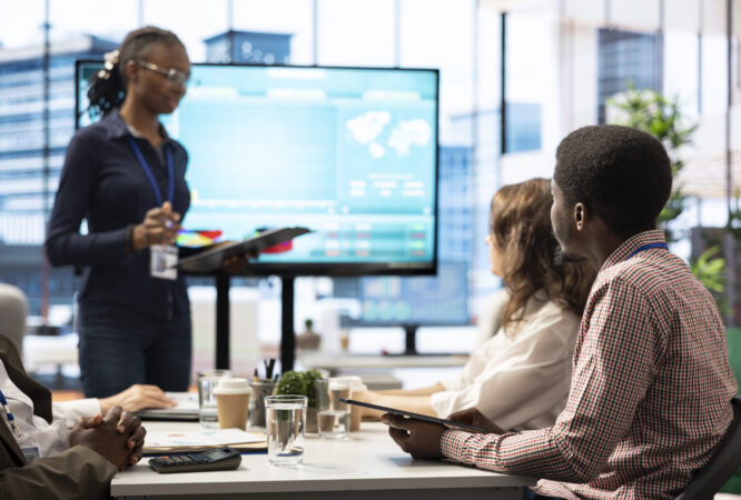 Coworkers engaging in a problem solving meeting at a corporation, using an interactive board to visualize data and develop solutions for complex business challenges. Analysis presentation.
