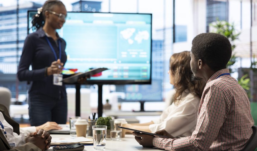 Coworkers engaging in a problem solving meeting at a corporation, using an interactive board to visualize data and develop solutions for complex business challenges. Analysis presentation.