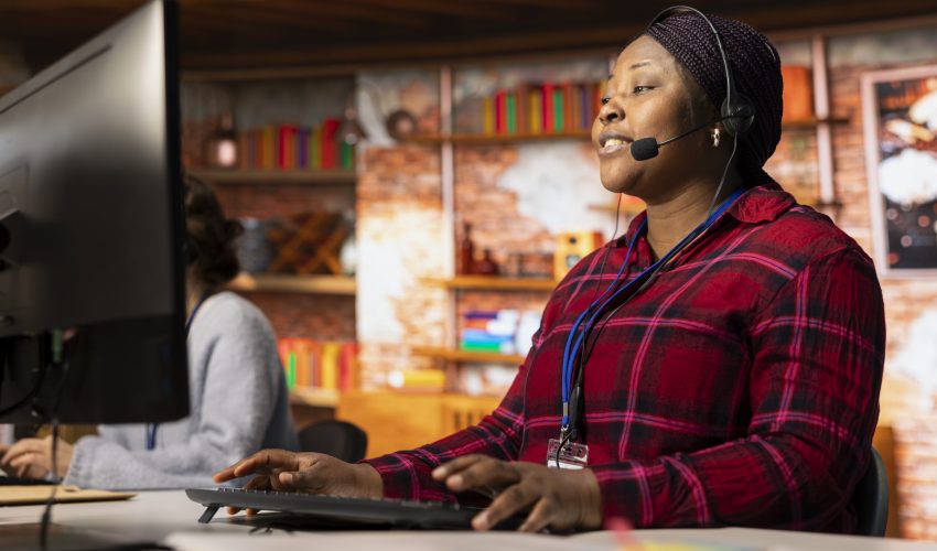 Jolly call center professional typing on PC keyboard, assisting customers through digital communication channels. Friendly customer support representative in live chat with client